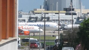 Escena a l'aeroport amb un avió d'Atlantic Airlines a la plataforma, envoltat d'infraestructures i vehicles estacionats.