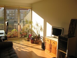 A living room with a sofa, TV, wooden cabinet, and potted plants. - Wifi 500mb, Apartment Lisbon, com Garagem e Varanda (Lisboa)