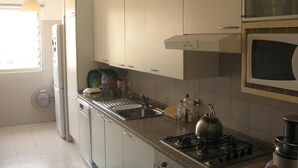 Cuina amb armaris blancs, fogó a gas, microones i rentaplat.