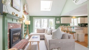 A cozy living room with a fireplace, a sofa, and a dining area. - 0.6 Miles to Beach Great for families! (South Chatham)