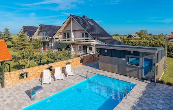 A modern house with a swimming pool, a wooden deck, and a brick wall.