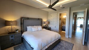 A modern bedroom with a large bed, a ceiling fan, bedside lamps, and a nightstand. - Two Bedroom Luxury Condo located in Beautiful February Point (George Town)