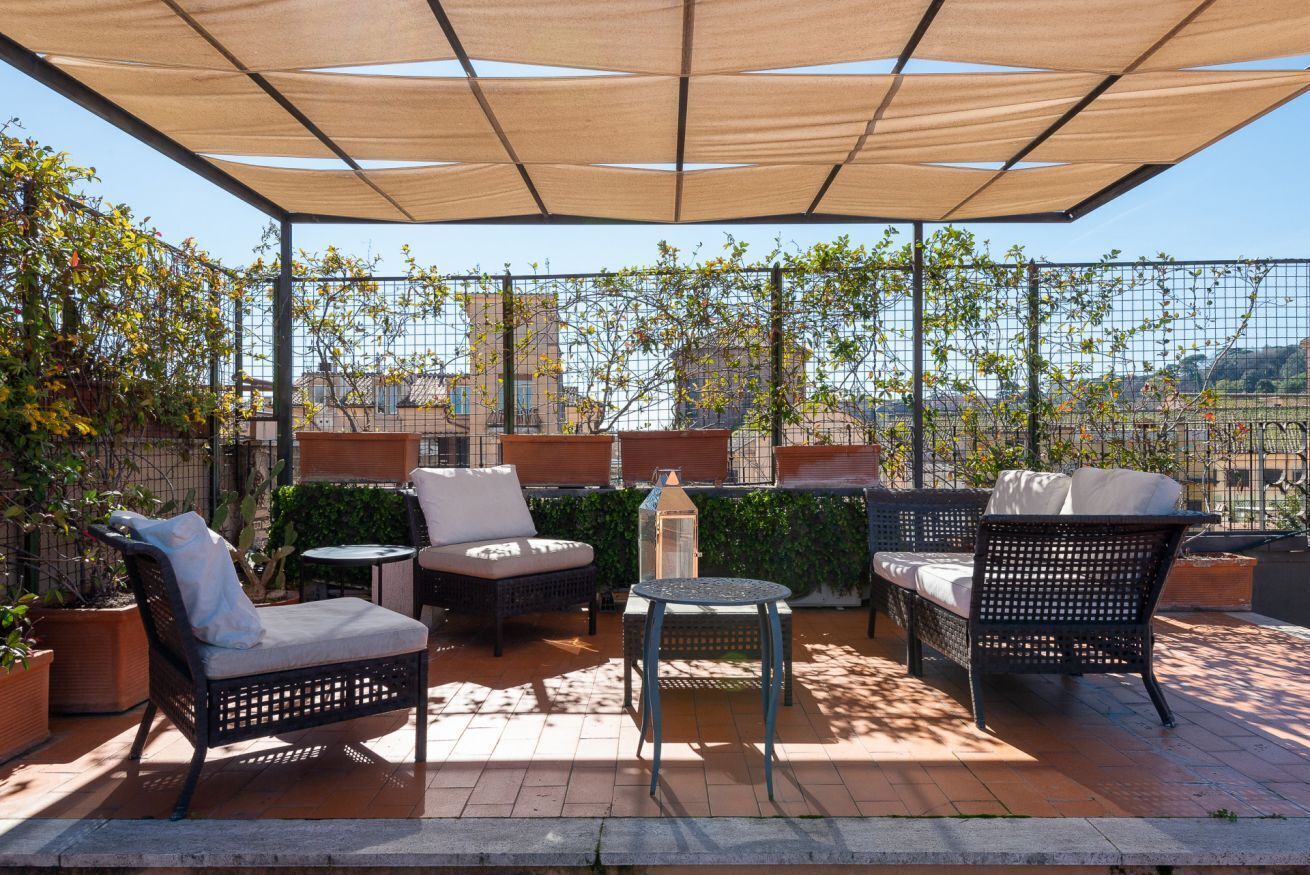 Eine Terrasse im Freien mit Korbmöbeln, einem Tisch und einer Laterne.