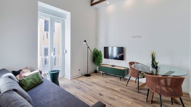 Ein modernes Wohnzimmer mit einer Couch, einem Glastisch und einem Fernseher an der Wand.