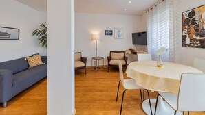 Un salon moderne comprenant un canapé, des fauteuils, une table à manger et un téléviseur.