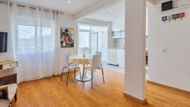 Un salon moderne avec un coin repas, un plancher en bois et une cuisine à l’arrière-plan.