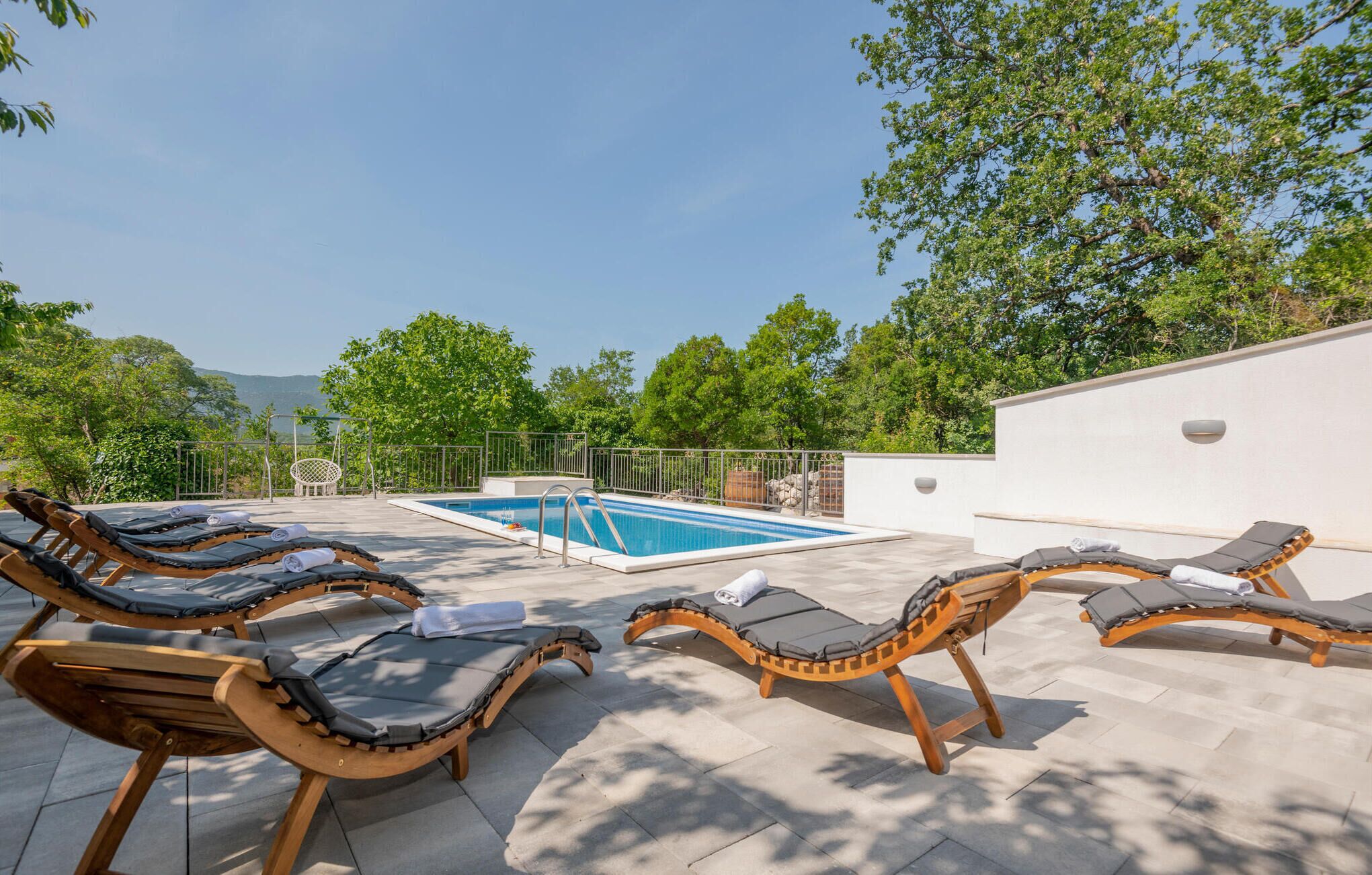 A poolside area with sun loungers and a swimming pool.