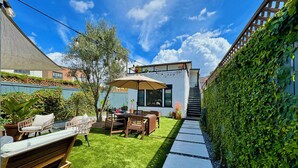 A patio with a table and chairs, a small garden, and a staircase leading to a covered area. - Historic & sunny beachside 2br with modern comforts (Marina del Rey)