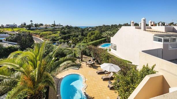 A rooftop pool area with a view of the sea, surrounded by lush greenery and modern architecture. - Casa Palm House - private pool in Carvoeiro (Carvoeiro)