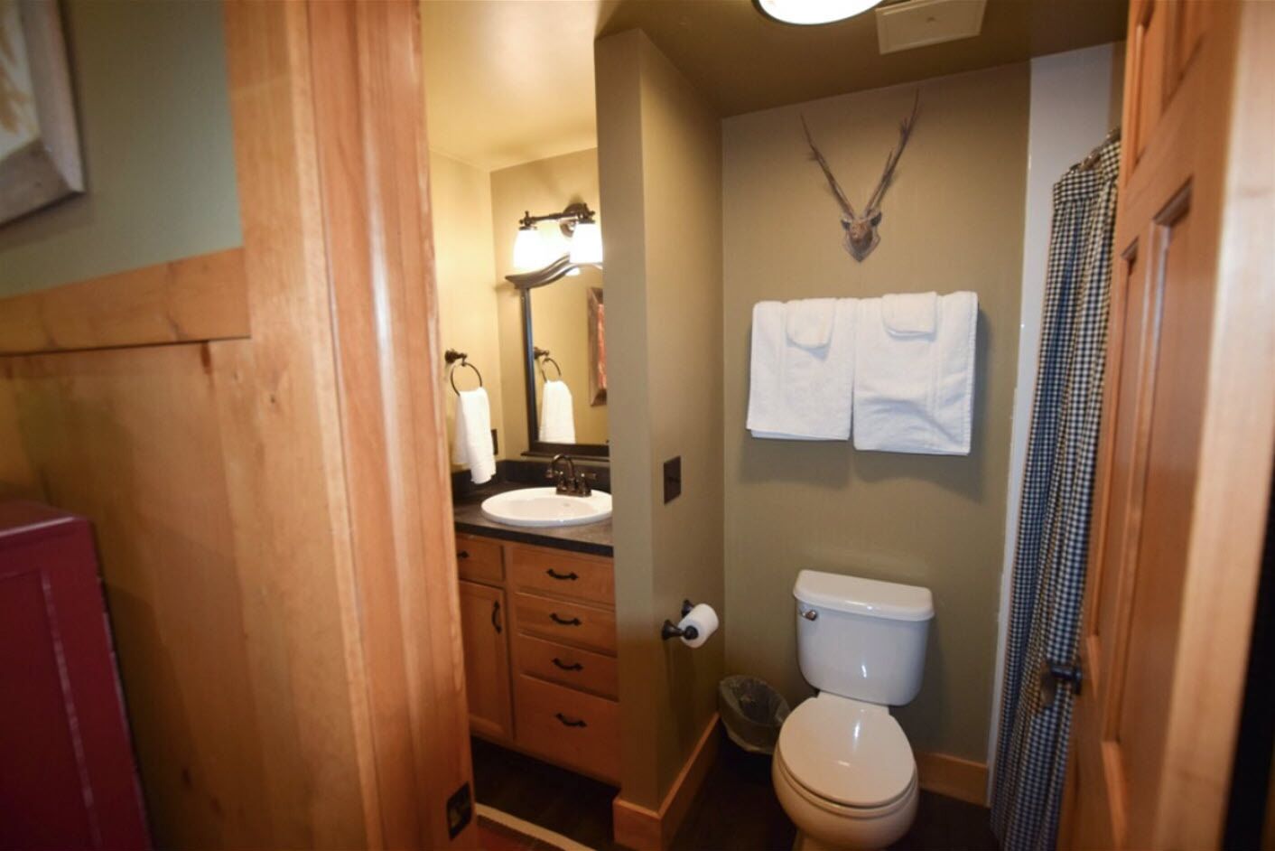 Un baño con tocador de madera, lavamanos, inodoro y zona de ducha.