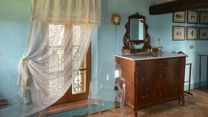 Una habitación con techo y cómoda de madera, un espejo y una ventana con cortina de encaje.