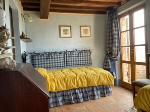 Ein Schlafzimmer mit einem Bett, karierten Vorhängen und einem Fenster mit Blick.