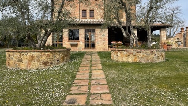 Una casa de piedra rústica con un patio central, rodeada de árboles.