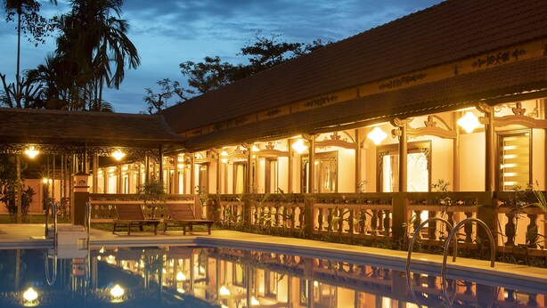 A poolside area with a reflection of the building's interior, a bench, and a railing. - Spatel d'Annam Boutique Spa & Hotel (Hue)