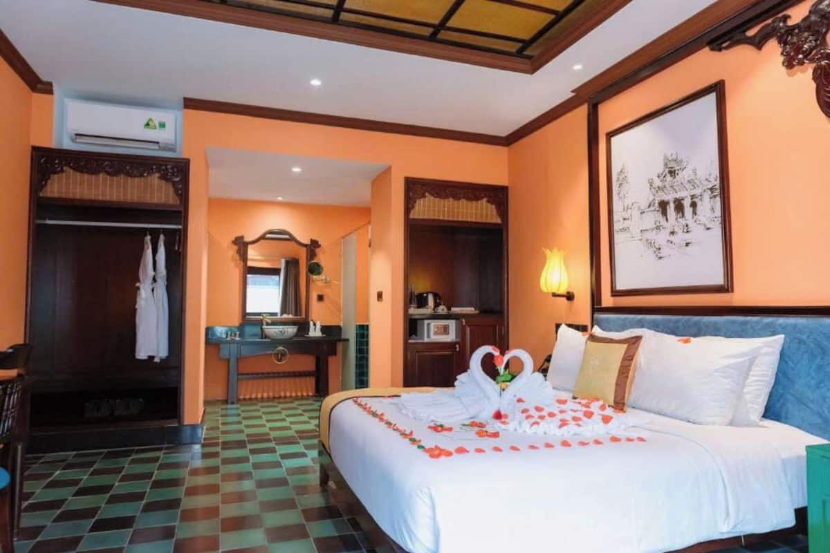 Una camera d'albergo con un letto, una toeletta con uno specchio, un lavandino e un armadio.