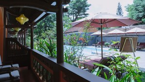 A covered outdoor area with a pool, lounge chairs, and umbrellas. - Spatel d'Annam Boutique Spa & Hotel (Hue)