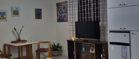 A living room with a sofa, coffee table, TV, and a refrigerator.