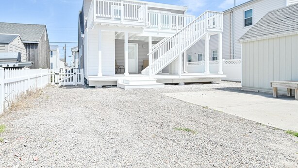 A two-story house with a white exterior, a front porch, and a staircase leading to the second floor. - "Island Time!" Steps 2 Beach & Downtown AC+Dogs OK (Brigantine)