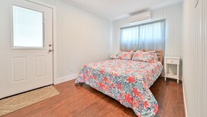 A bedroom with a floral bedspread, a wooden floor, a white door, and a window with blinds. - "Island Time!" Steps 2 Beach & Downtown AC+Dogs OK (Brigantine)