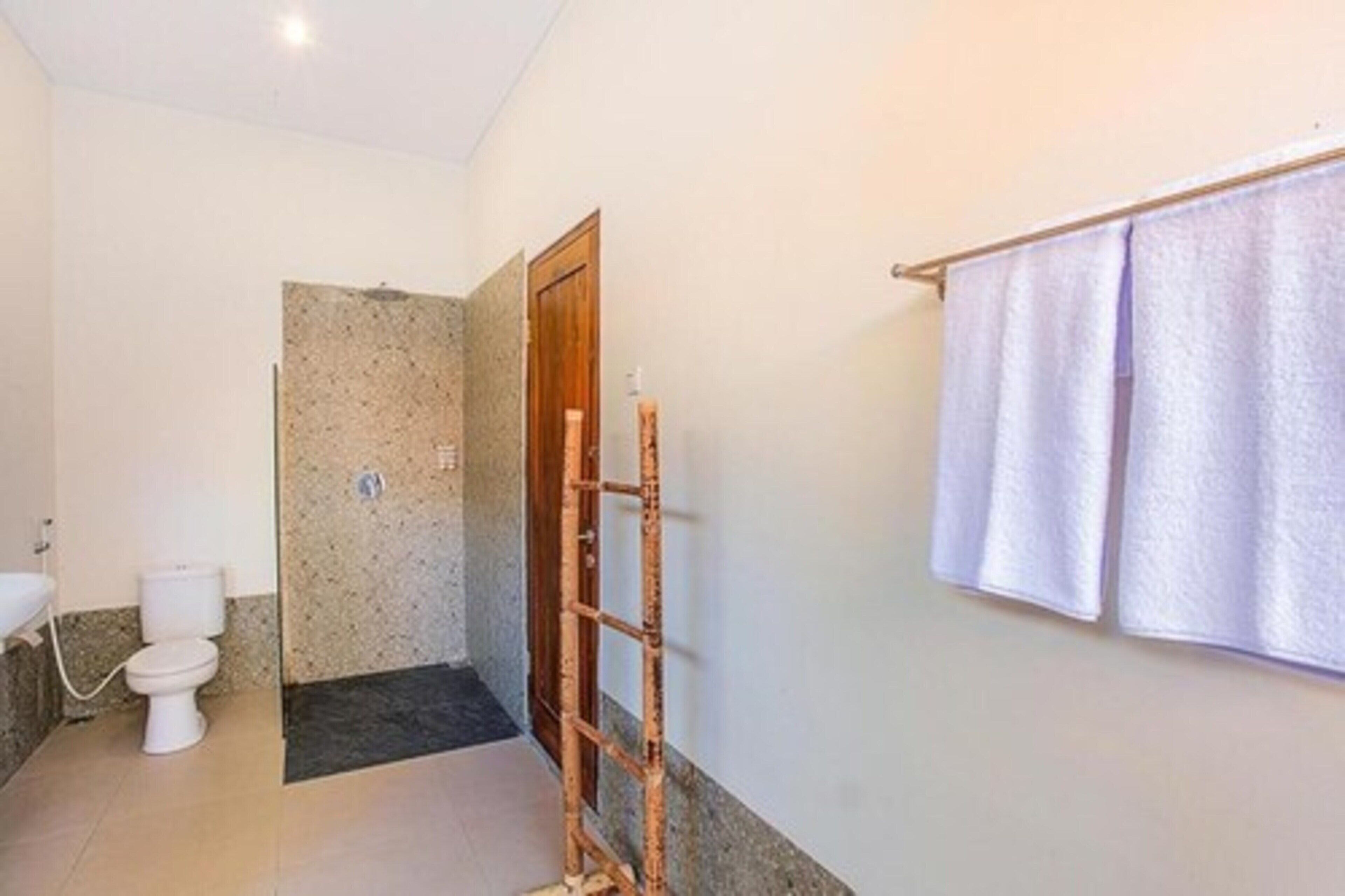 Un baño con inodoro, zona de ducha y toallero.