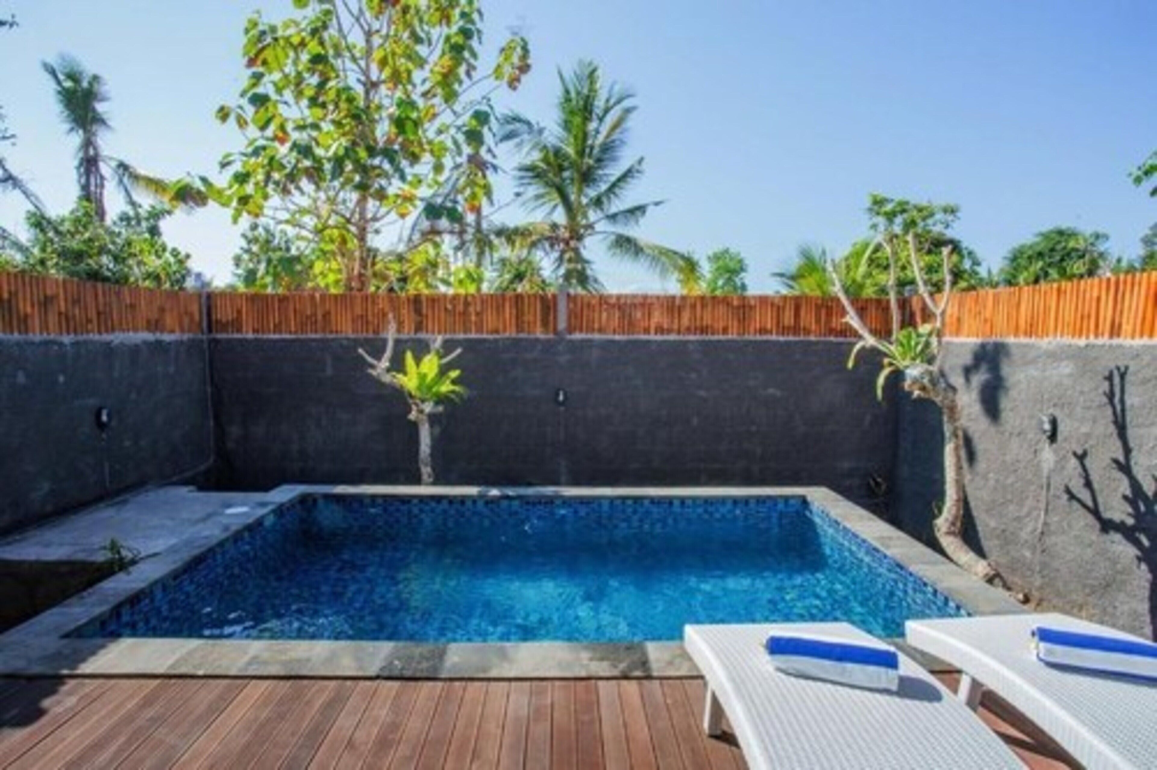 A rectangular swimming pool with a wooden deck and lounge chairs.