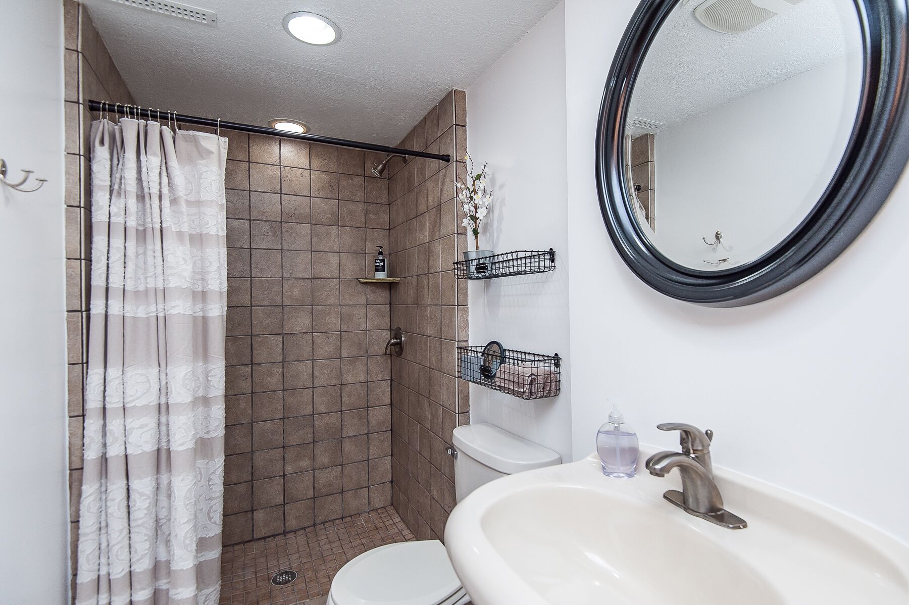 Un baño con ducha, inodoro, lavabo y espejo.