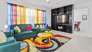 A living room with a green sofa, yellow coffee table, and a colorful rug. - Vibrant & Enchanting! Hot Tub! Walk to the Beach! (Pass Christian)
