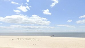 A wide sandy beach with a clear sky and a calm sea. - Vibrant & Enchanting! Hot Tub! Walk to the Beach! (Pass Christian)