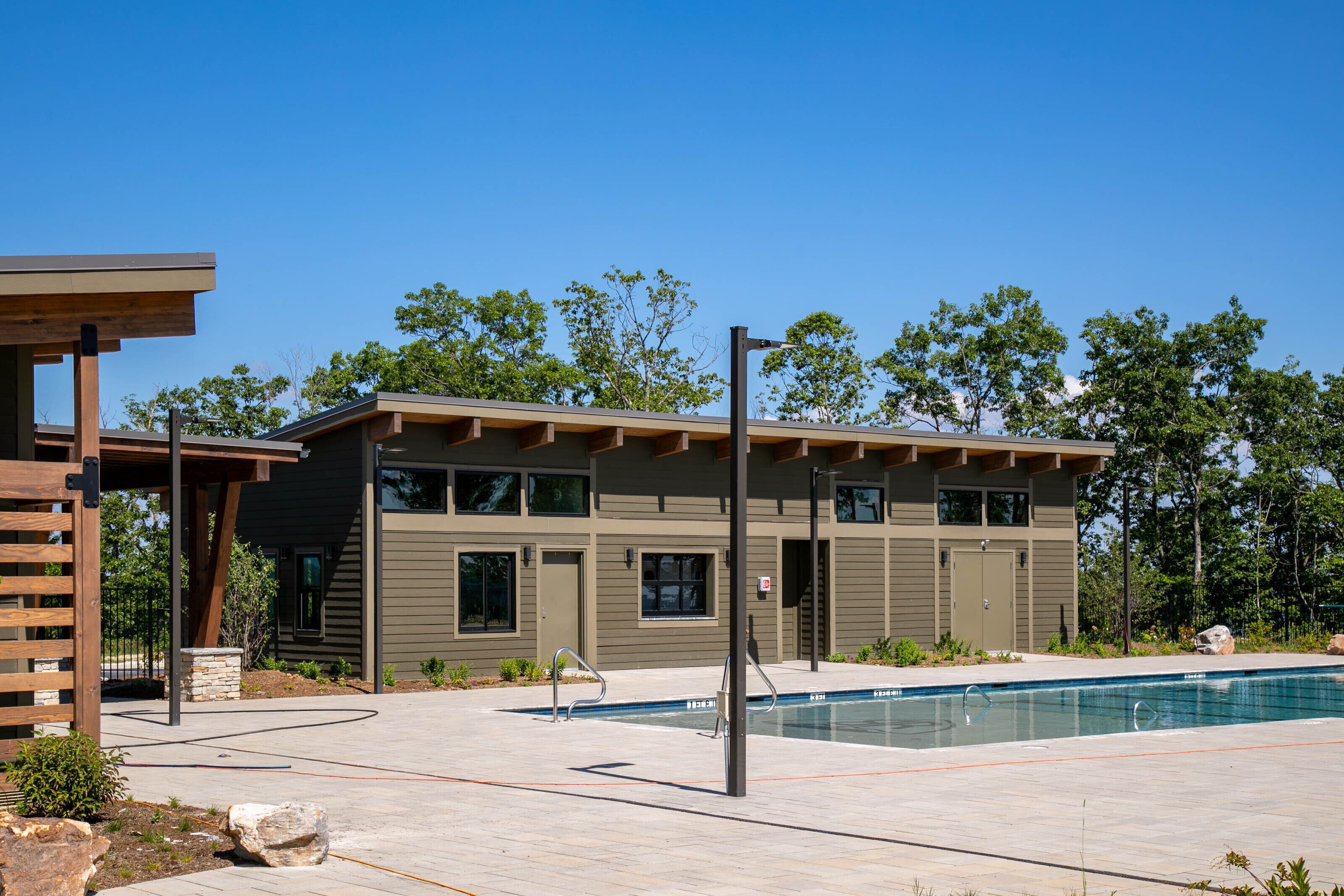 A modern building with a pool, outdoor seating, and a pergola.