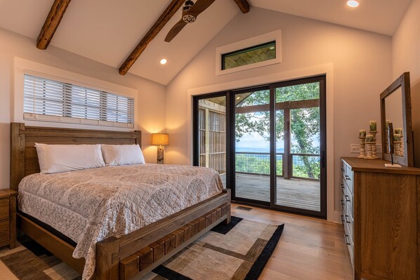 Un dormitorio con una cama grande, cabecera de madera y vistas a través de un ventanal corredero.