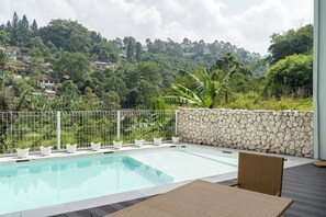 A swimming pool with a stone wall and potted plants, surrounded by a metal fence. - Lavender Rooftop 3BR Villa with a Heated Private Pool (Cimenyan)