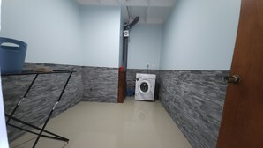 A laundry room with a washing machine, a drying rack, and a blue basin. - Apetahi - Bord de lagon (Raiatea)