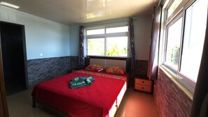 A bedroom with a bed, a window, and a nightstand. - Apetahi - Bord de lagon (Raiatea)