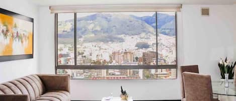 A modern living room with a large window offering a cityscape view, a sofa, a coffee table, and a chair.
