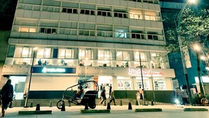 Un edificio de varios pisos con ventanas iluminadas y una tienda en la planta baja.
