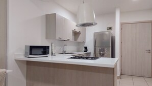 Una cocina moderna con microondas integrado, cafetera y refrigerador de acero inoxidable.