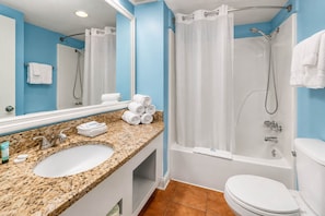 A bathroom with a granite countertop, a white sink, a mirror, a shower with a glass door, and a toilet.