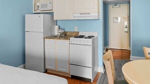 A compact kitchen with white cabinets, a stove, a microwave, and a refrigerator. - Sea Mist 20909 (Myrtle Beach)