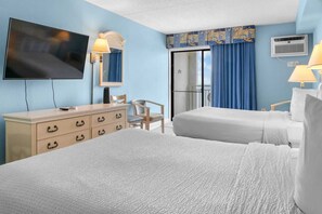 A hotel room with two beds, a TV, a dresser, a chair, and a balcony with curtains.