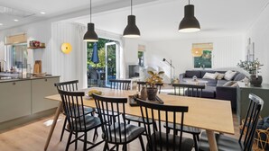 A modern kitchen with a dining area, a sofa, and a large window.