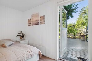 Una camera da letto con un letto, un comodino, una finestra e vista su una terrazza.