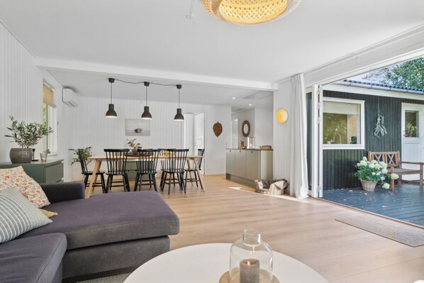 A modern living room with a sofa, dining table, and pendant lights.