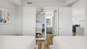 Habitación con dos camas, ventilador de techo y baño visible a través de una puerta abierta.