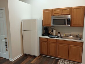 Compact kitchen area with a refrigerator, microwave, and coffee maker.