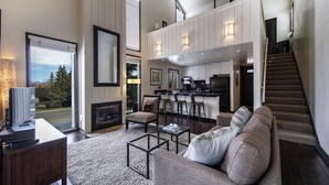 A spacious living room with a large sofa, a fireplace, and a kitchen area with bar stools.