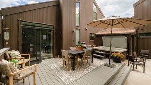 An outdoor patio with a table and chairs, a hot tub, and a pergola with an umbrella.