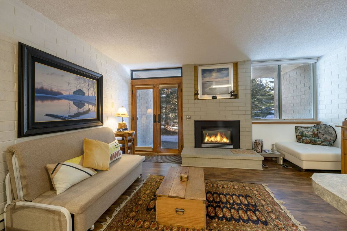 Ein Wohnzimmer mit Kamin, einer Couch, einem Couchtisch und einem Teppich.