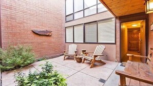 A patio area with two Adirondack chairs, a small table, and a wooden bench.