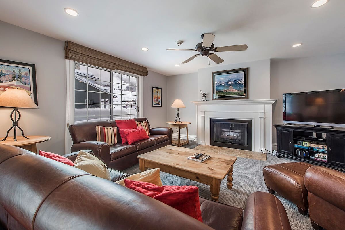 A living room with leather sofas, a wooden coffee table, a fireplace, and a television.