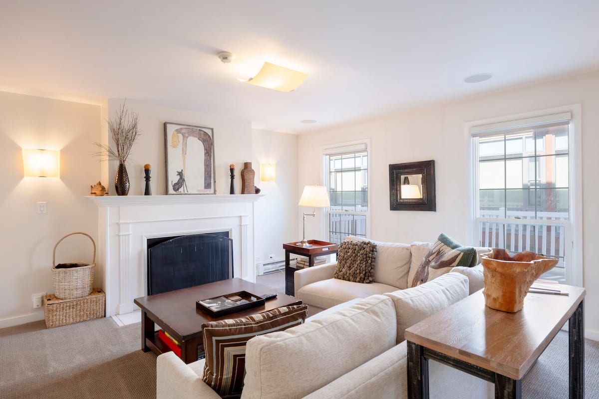 A living room with a fireplace, a sofa, a coffee table, and a side table with a lamp.
